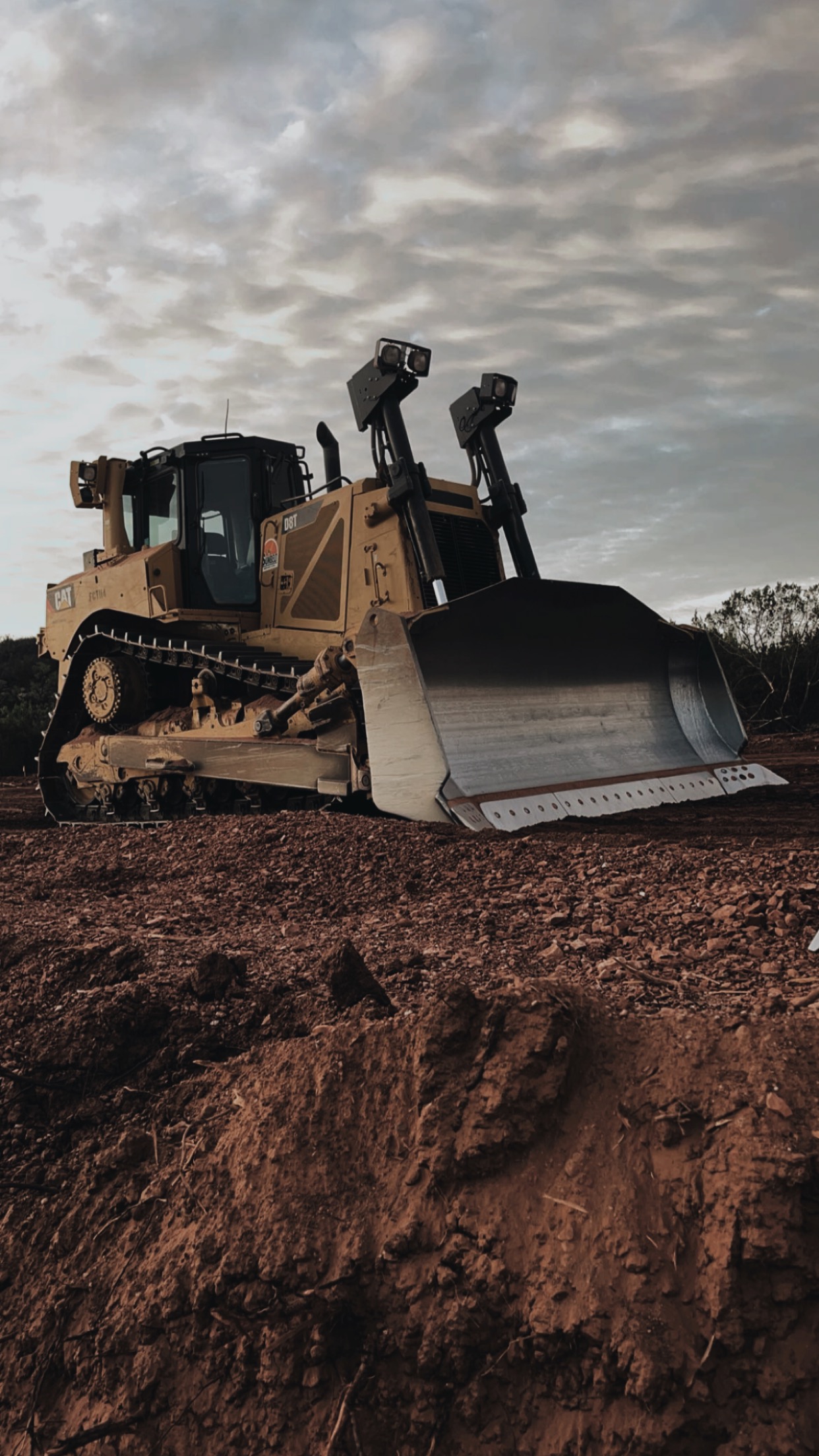 CAT D8T dozer on red dirt beneath a cloudy sky